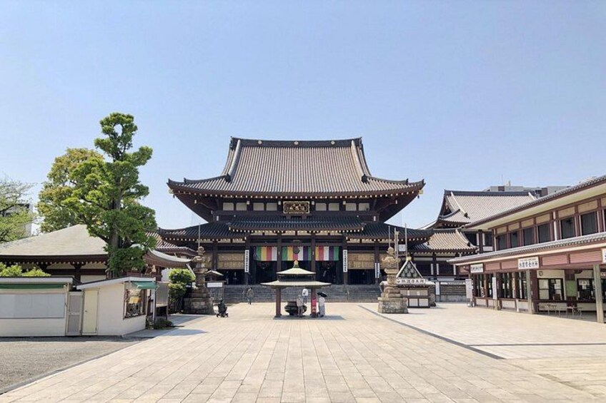 En traditionell japansk byggnad med en innergård belagd med plattor, omgiven av mindre byggnader och träd. 1