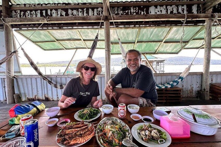 Two people sitting at a table with various dishes and drinks. 1