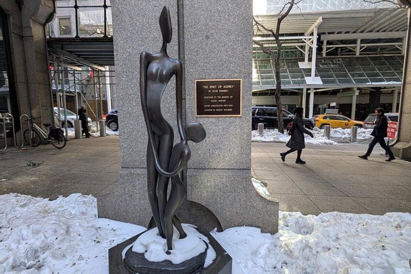 A sculpture of a woman holding a child in a snowy urban setting. 2