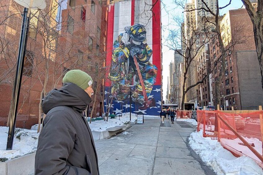 A person walking on a snow-covered sidewalk with a colorful mural in the background. 5