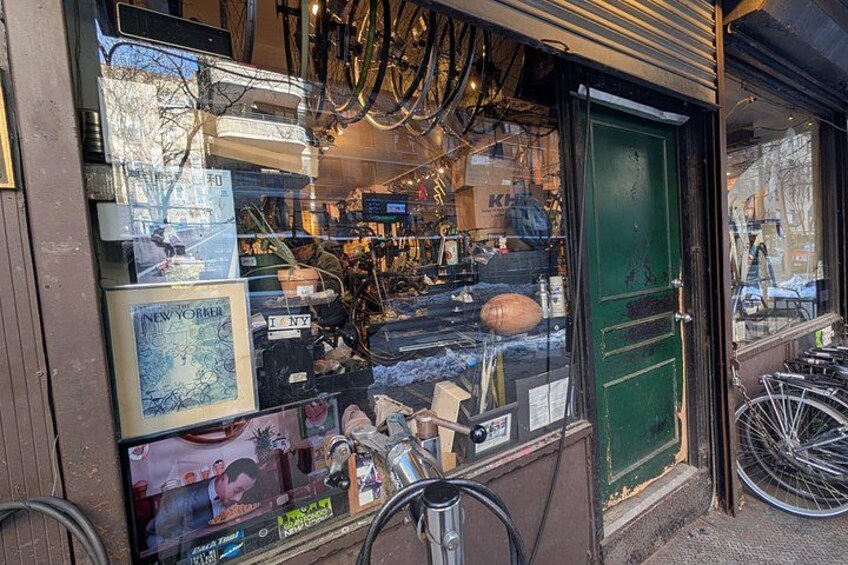 A storefront with a green door, bicycles outside, and various items displayed in the window. 4