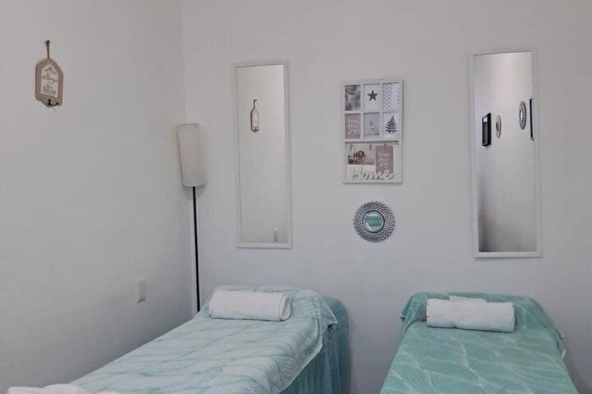A bedroom with two beds, a mirror, a wall clock, and a decorative plate. 3