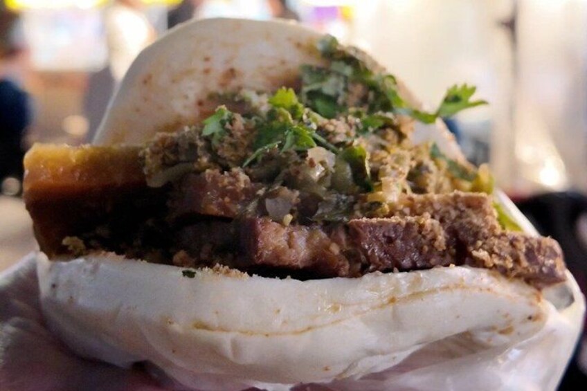 A food item with a white base, topped with a dark brown substance, green herbs, and a yellowish sauce. 2