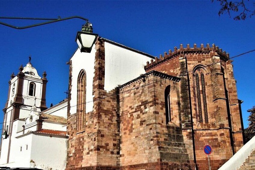 A historic church with a bell tower and a clock, surrounded by a clear blue sky. 4