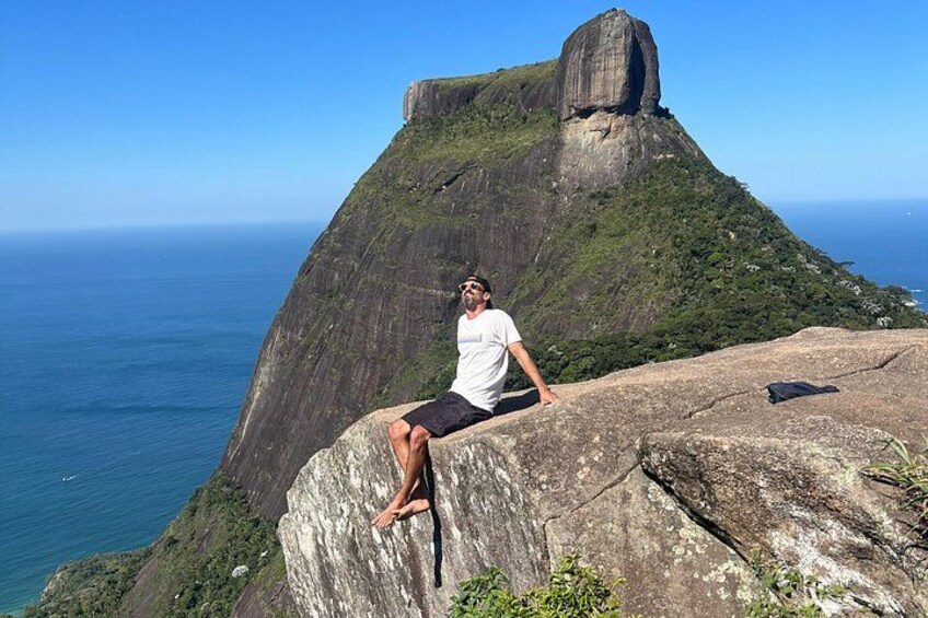 A person sitting on a rock with a large mountain in the background. 3