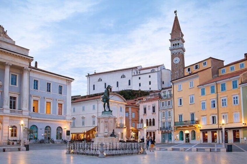 A historic square with a statue, a clock tower, and classical architecture. 4