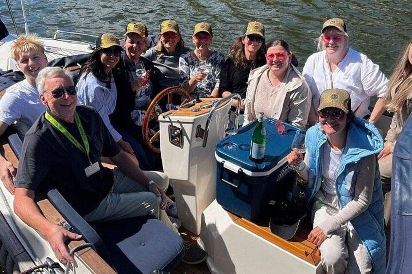 A group of people on a boat with a steering wheel and a cooler. 5