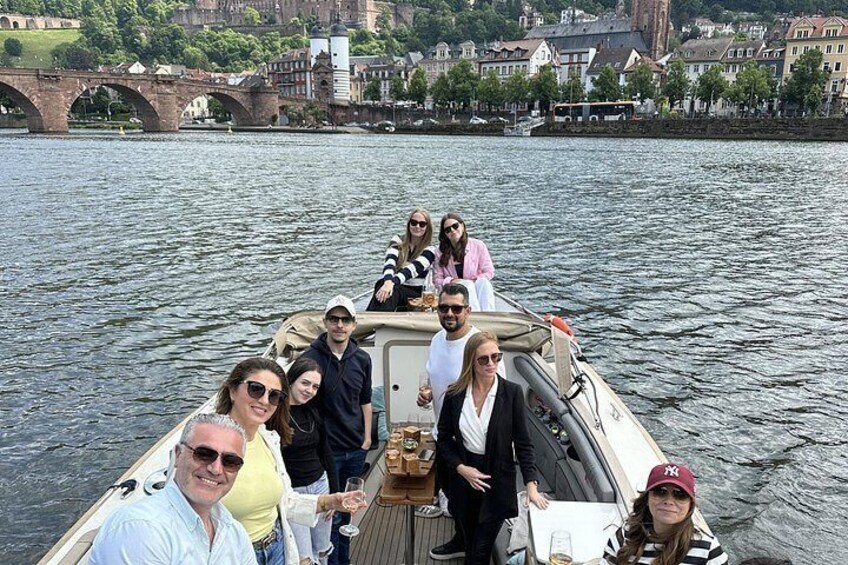 A group of people on a boat with a bridge and buildings in the background. 3