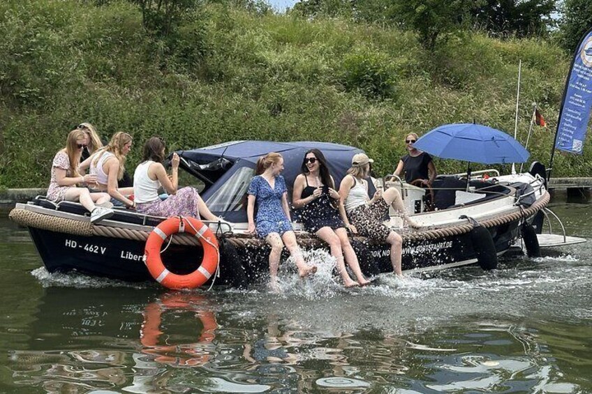 A boat with people on it, water, and greenery in the background. 4