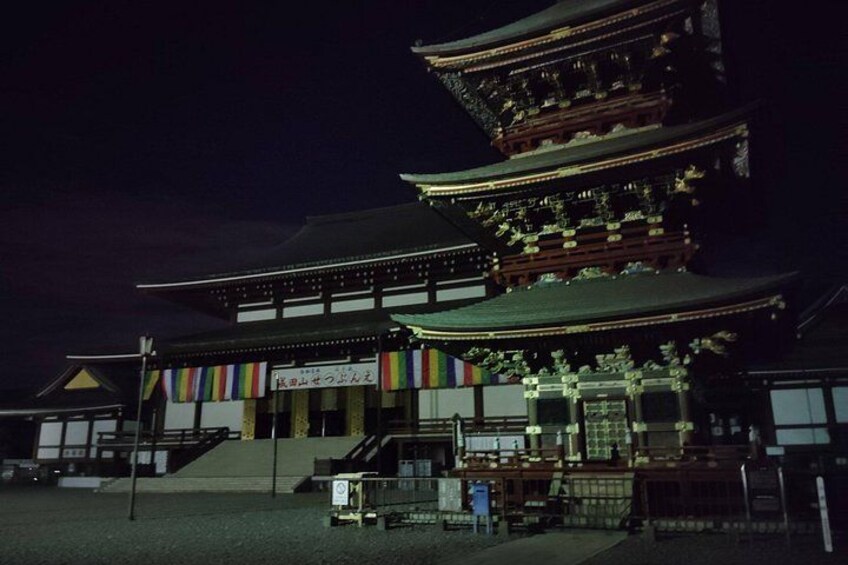 Ein traditionelles japanisches Gebäude bei Nacht mit mehreren Ebenen und einer Werbetafel. 2