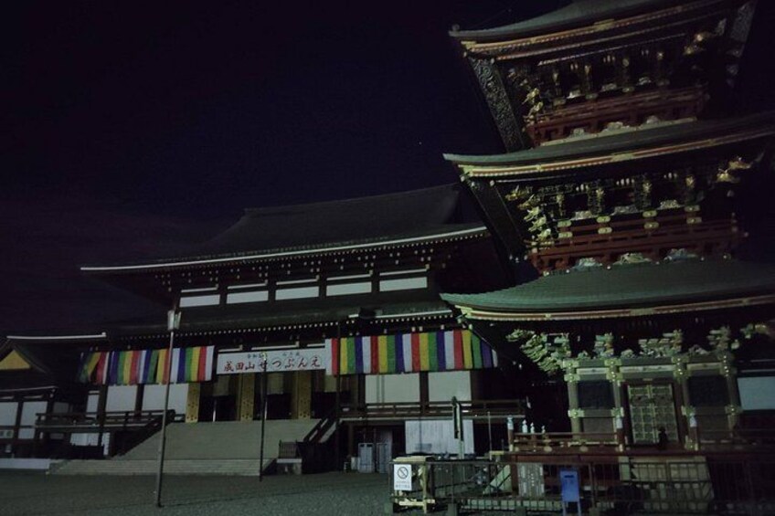 Ein traditionelles japanisches Gebäude mit mehreren Ebenen und einem farbenfrohen Banner am Eingang. 3
