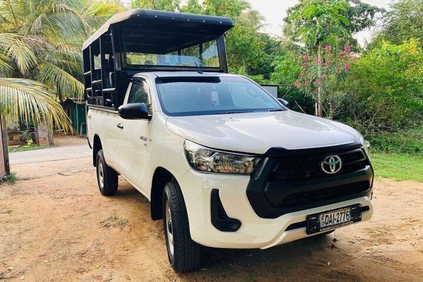 A white Toyota pickup truck with a black cargo bed parked on a dirt path. 3
