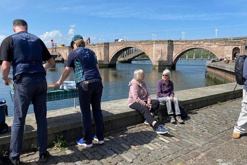Personas cerca de un río con un puente al fondo. 2