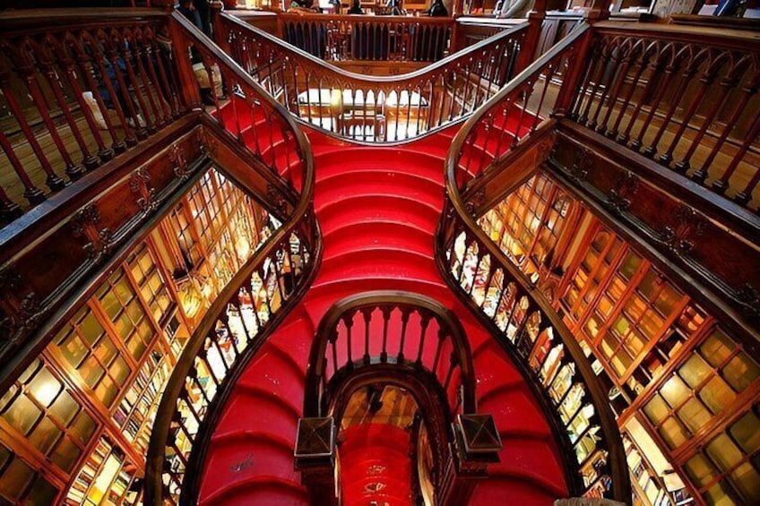 Un magnifique escalier avec des marches rouges et des rampes richement décorées, entouré d’étagères à livres. 2