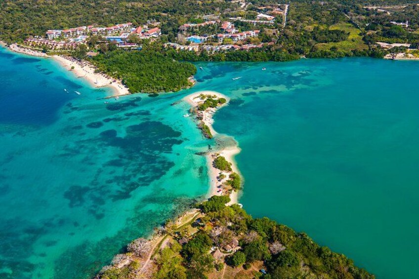 A coastal landscape with a beach, a small island, and a resort area. 3