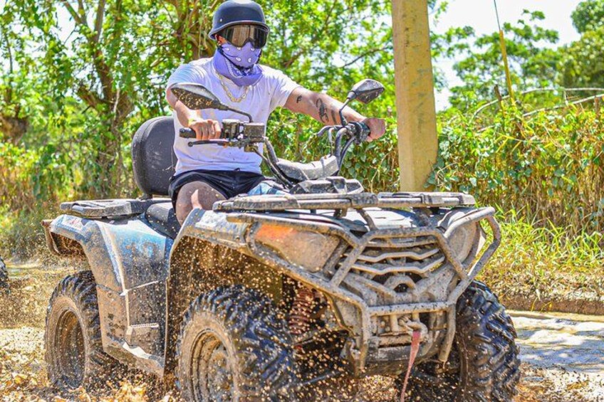 A person riding an ATV on a dirt path with trees in the background. 3