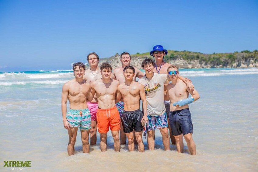 A group of people standing on a beach with ocean waves in the background. 3