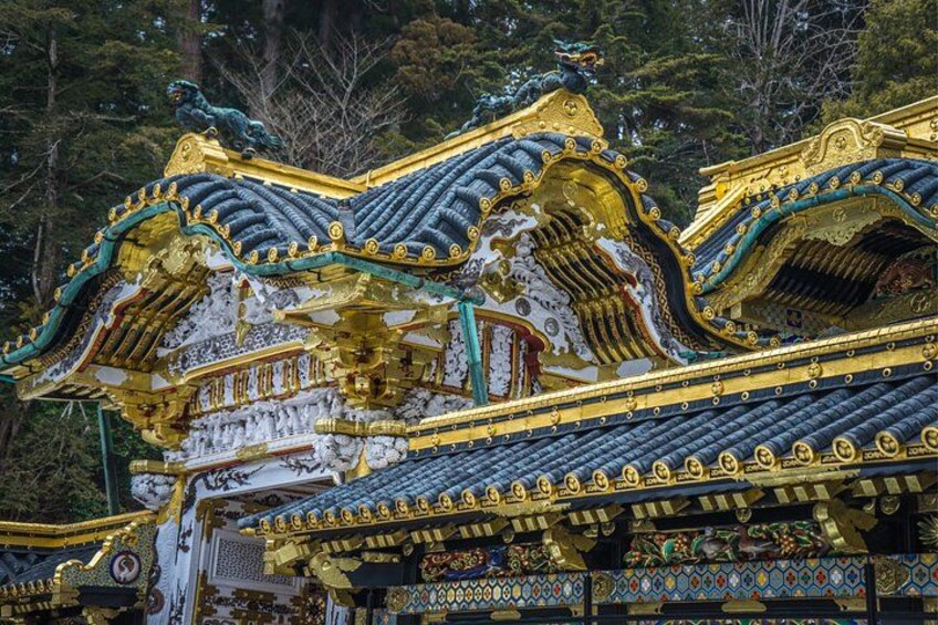 A traditional Japanese temple with ornate golden and blue roof tiles, intricate patterns, and statues. 1
