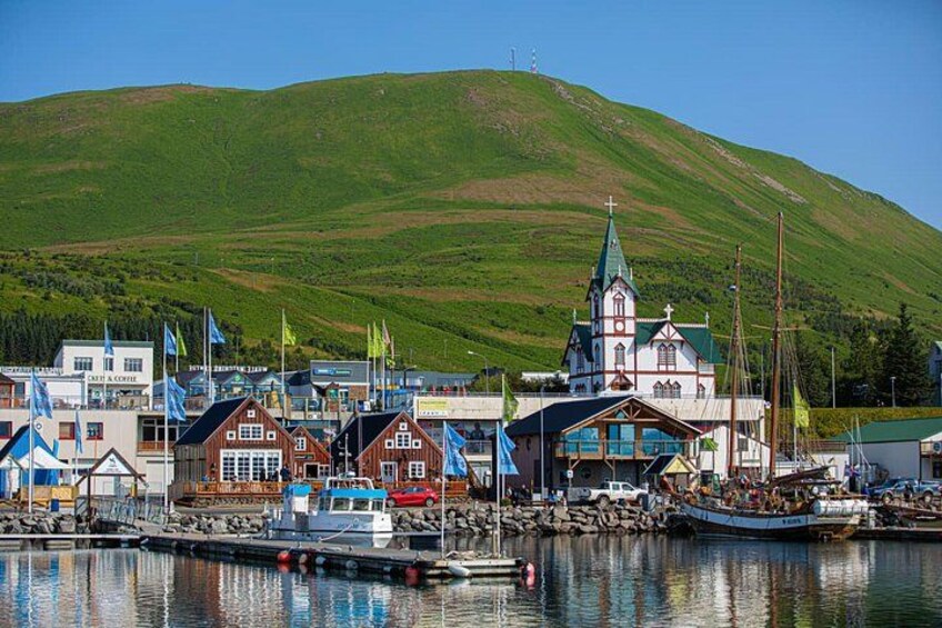 A harbor with boats, a church, and a hill in the background. 2