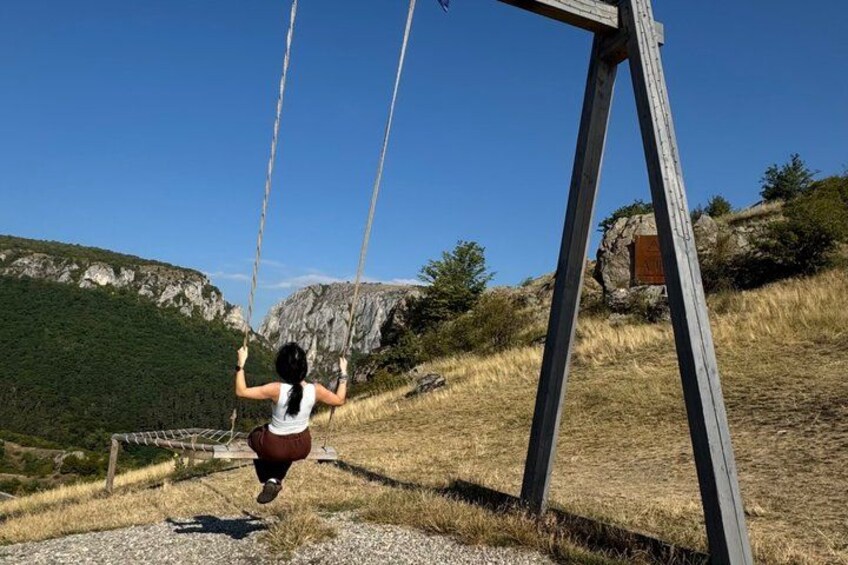 A person on a swing in a mountainous area with a clear sky. 2
