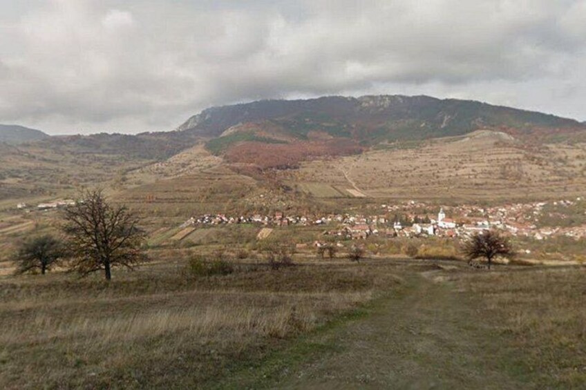 A rural landscape with a village, rolling hills, and a church. 3