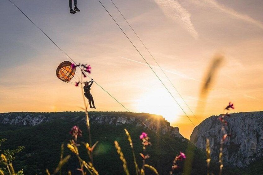 A person performing a high-wire act with a safety net, set against a sunset with a mountainous landscape in the background. 5