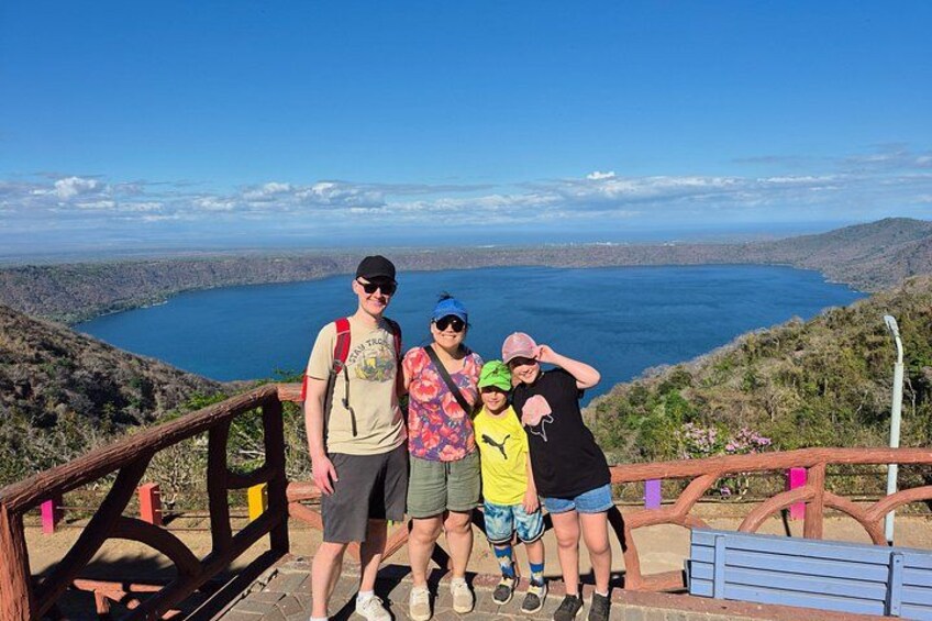 A group of people standing on a wooden observation deck overlooking a lake. 4