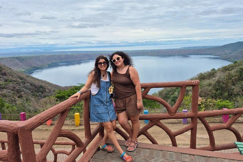 Two people standing on a wooden observation deck overlooking a lake. 3