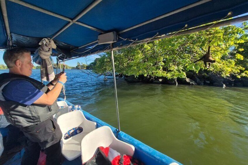 A person fishing from a boat with a net, surrounded by calm water and greenery. 5