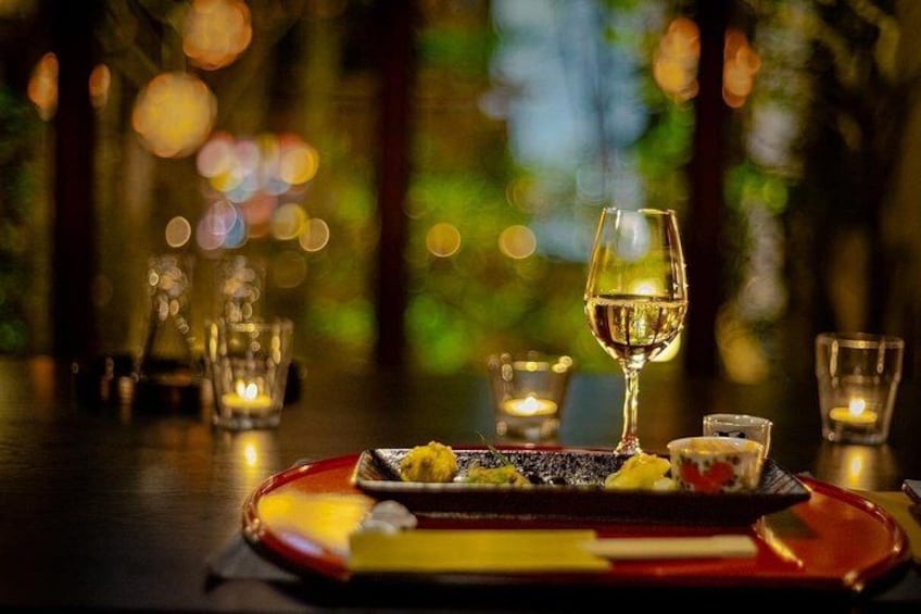 A dimly lit dining table with candles, a wine glass, and a plate of food. 1