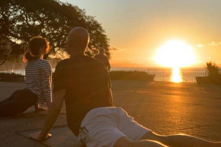 A sunset over a body of water with a person sitting on a mat. 1