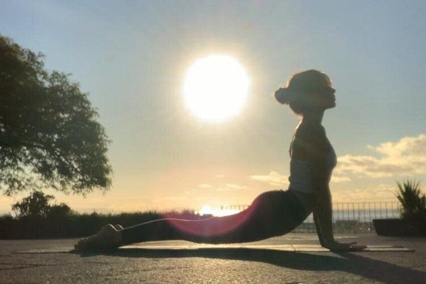 A person performing a yoga pose outdoors with the sun low in the sky. 4