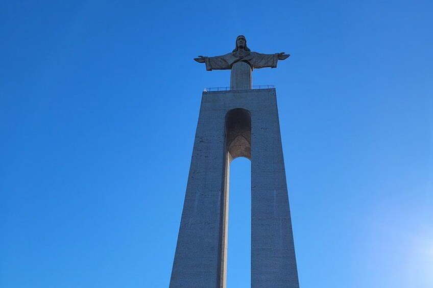A tall monument with a statue on top against a clear blue sky. 2