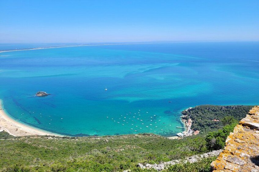 A coastal landscape with clear turquoise waters, a sandy beach, and a rocky cliff. 4