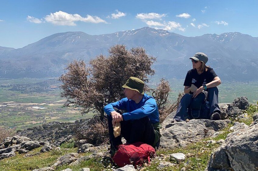 Two people sitting on a rocky outcrop with a mountainous landscape in the background. 5