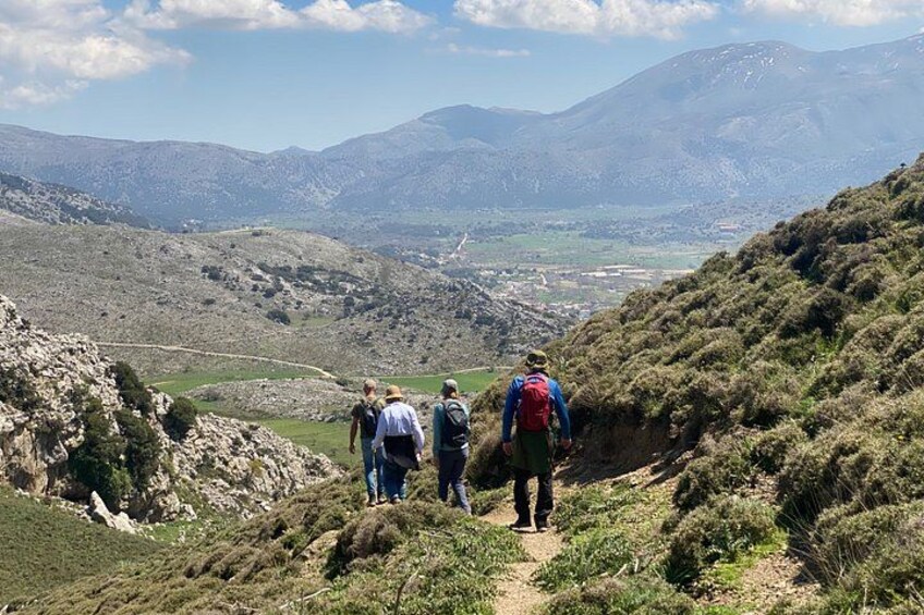 A group of hikers on a mountain trail with a valley and distant mountains in the background. 4