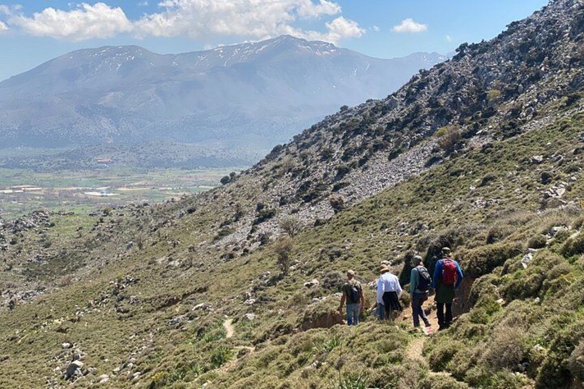 A group of hikers on a mountainous trail with a valley and distant mountains in the background. 3