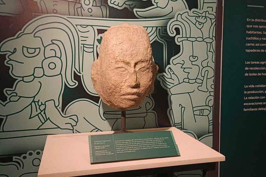 A stone sculpture on a pedestal with a green informational plaque. 2