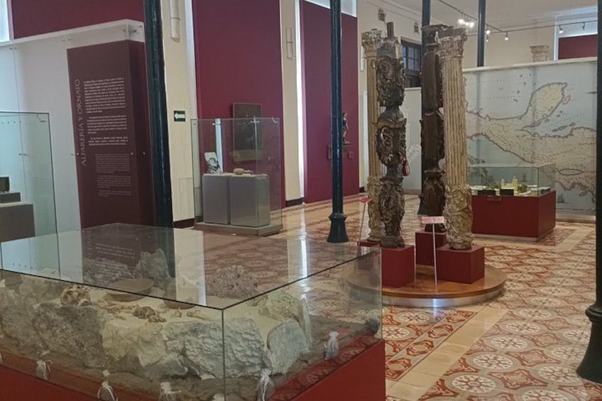A museum interior with marble flooring, glass display cases, and ancient columns. 5