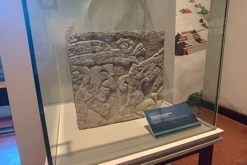 A stone relief sculpture in a glass display case. 1