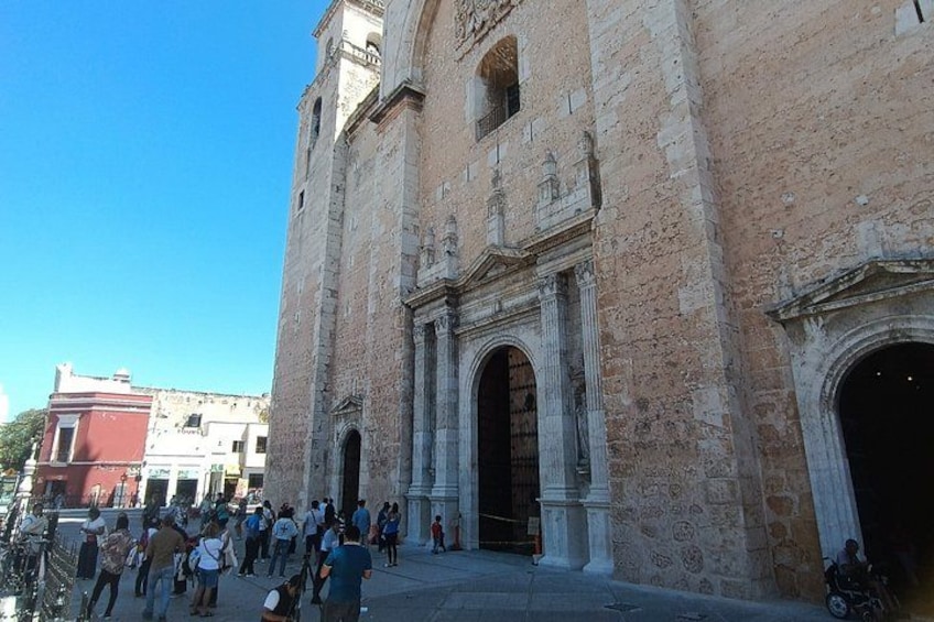 A historic building with large arched doorways and a crowd of people outside. 3