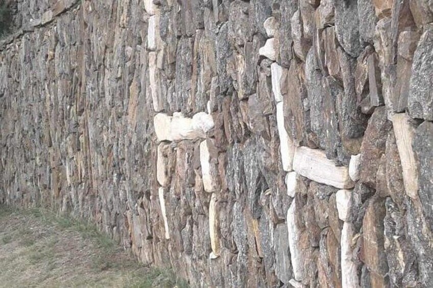 A rock wall with carved wooden figures. 3