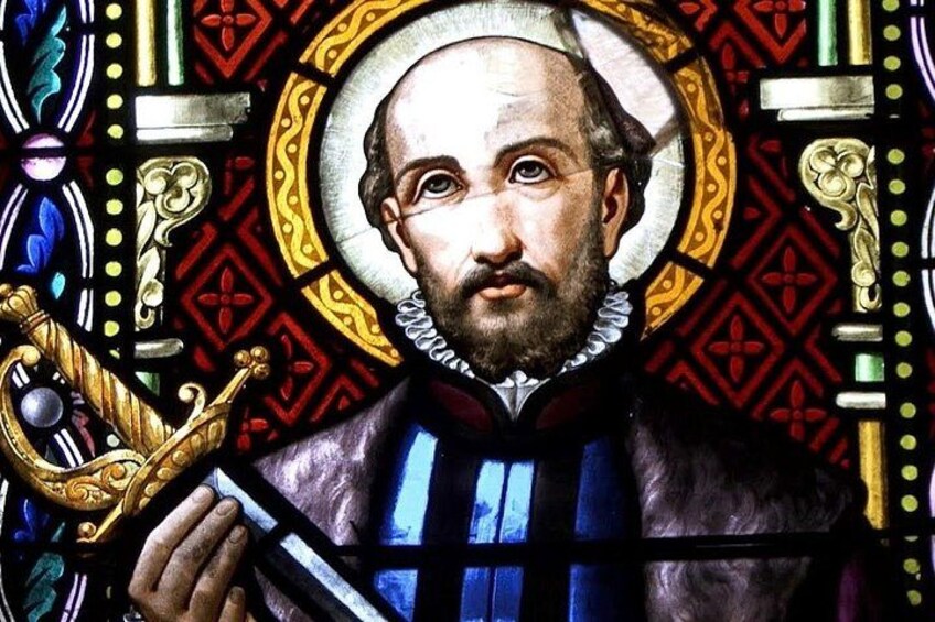A stained glass window with a central figure holding a book, surrounded by ornate patterns and designs. 4