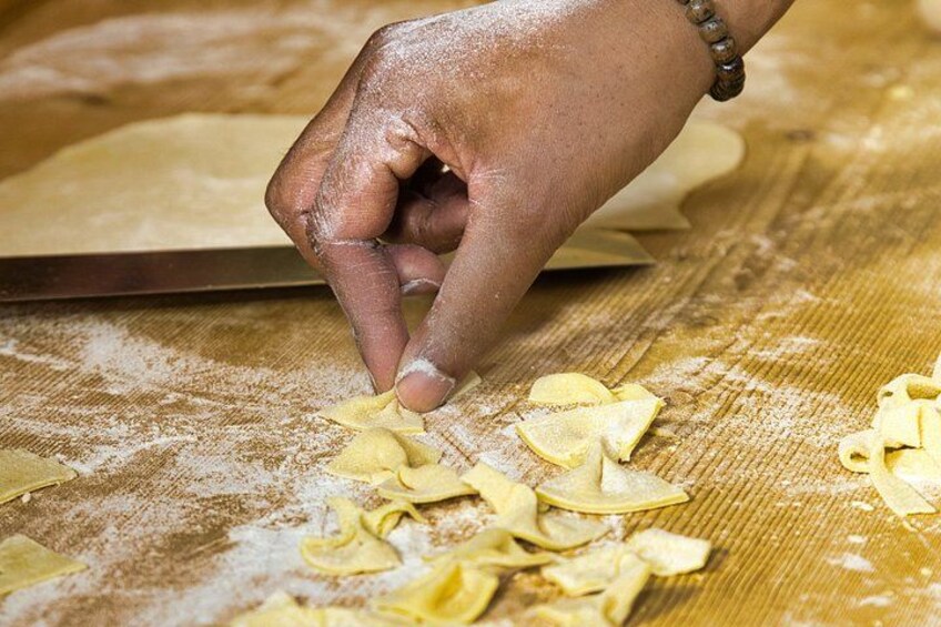 A hand shaping pasta dough on a floured surface. 5