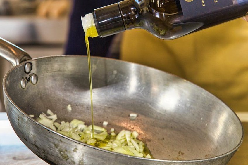 A frying pan with chopped onions and oil being poured into it. 3