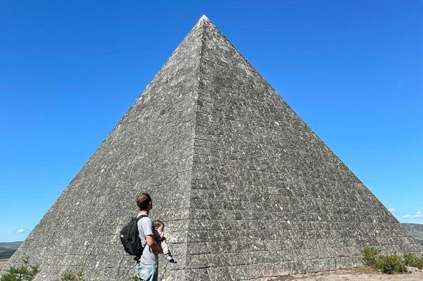 A large pyramid with a person and a child standing in front of it. 1