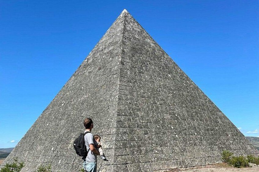 A large pyramid with a person and a child standing in front of it. 1