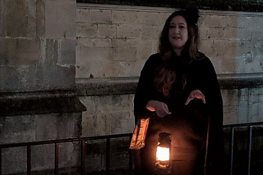 Una persona de pie frente a un muro de piedra con una fuente de luz al fondo. 4