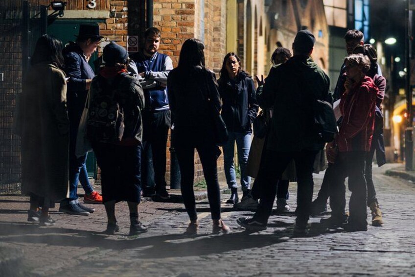 Un grupo de personas de pie en una calle empedrada de noche. 3
