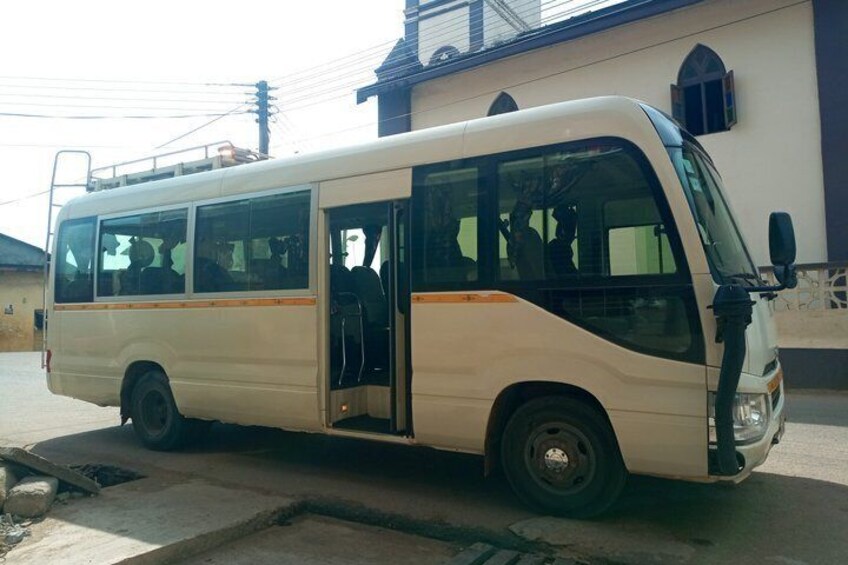 A white bus parked on a street with a building in the background. 2
